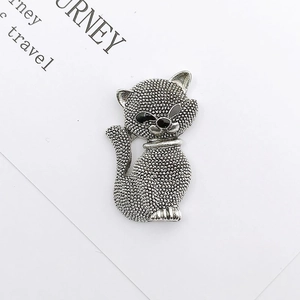 Macro shot of silver zinc alloy cat charm with dotted texture on a white travel card