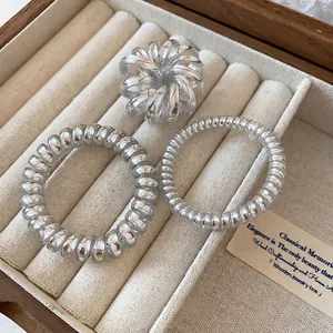 Three-piece silver spiral telephone wire hair ties set displayed in a wooden jewelry box