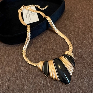 Macro detail of vintage gold snake chain necklace with black enamel fan pendant