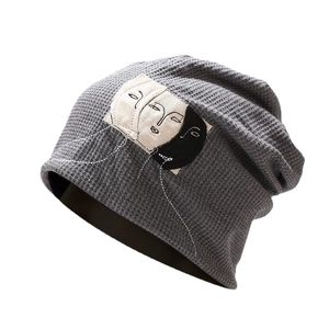 Dark grey waffle knit beanie featuring artistic embroidered face patches for a casual style