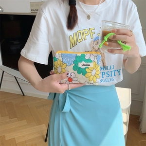 Detailed view of a handheld floral cosmetic bag with colorful patterns and a zip closure
