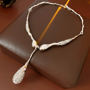 Gros plan d'un collier argenté irrégulier serti de strass sur un coffret marron texturé