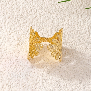 Detail of golden open ring featuring a leaf pattern and hammered texture finish