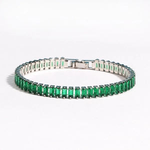 Detailed close-up of emerald green rectangle zircon stones set in a silver tennis bracelet