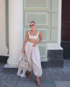 Detail of beige three-piece set featuring cropped vest, lantern pants, and matching accessories