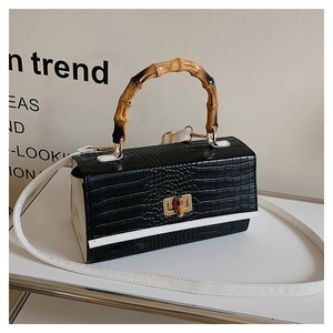 Detail of crocodile embossed leather bag with iconic bamboo handle and gold buckle