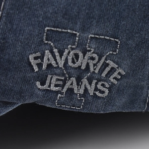 Macro shot of grey silk embroidery showing Favorite Jeans detail on denim fabric