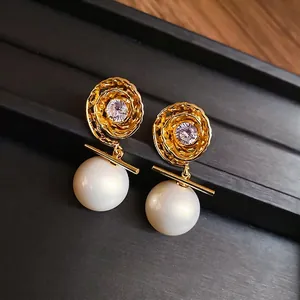 Boucles d'oreilles vintage dorées avec fleur en zircon et perles sur plateau noir