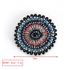 Detailed macro view of 70mm embroidered evil eye brooch with colorful beads and crystal