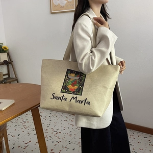Close-up of a linen tote bag featuring artistic portrait print and Santa Marta text