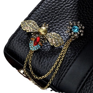 Black pebbled leather brooch with golden bee and blue rhinestone flower chain tassel