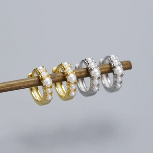 Macro detail of gold and silver S925 sterling silver pearl hoop earrings on display