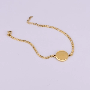 Golden Figaro chain bracelet with a polished round charm on a soft purple background