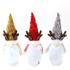 Three Christmas gnome wine bottle covers with sequin hats and striped bodies on white background