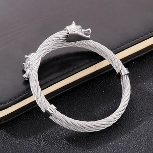 Detailed close-up of a silver wolf head bangle with braided steel cable texture