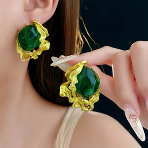 Close-up of vintage emerald green earrings with gold textured frames on model