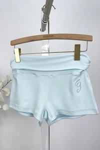 Close-up of light blue modal shorts with rhinestone G logo on high fold-over waistband