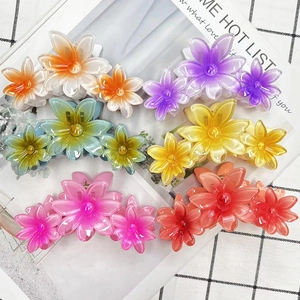 Flat lay of floral claw clips in vibrant gradient resin colors on a checkered fabric