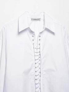 Detailed view of white V-neck shirt featuring silver metal eyelets and cross-tie lacing