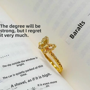 Elegant gold butterfly open ring with hollow texture and twisted rope band on book