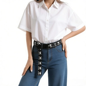 Black canvas belt featuring white skull prints and a round metal buckle on blue jeans