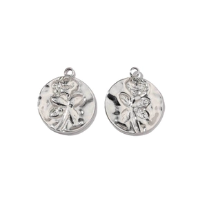 Detailed macro view of two round silver charms with embossed rose and leaf designs