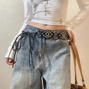 Vintage punk leather waist belt with silver metal rings and rivets on blue jeans