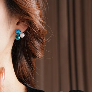 Macro shot of a triangular earring with blue crystals and a white round pearl