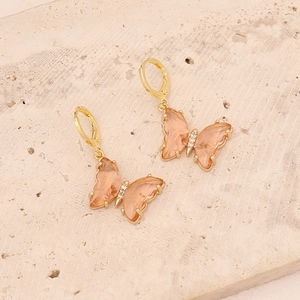 Close-up of champagne pink butterfly drop earrings with gold frame and micro-inlay