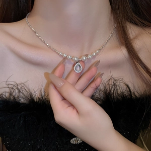 Detailed close-up of a pearl necklace with a teardrop pendant and pave-set diamonds