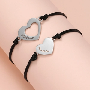 Detail of mother and daughter braided cord bracelets with engraved heart charms
