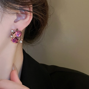 Macro shot of rose gold flower earrings with purple beads and sparkling diamonds