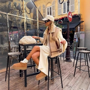 Women's beige faux shearling vest paired with white knit midi dress and platform boots
