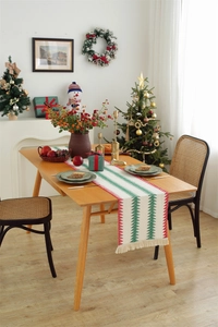 Close-up of linen woven table runner featuring festive Christmas tree patterns and tassels