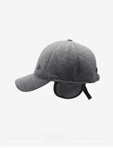 Close-up of a dark grey knit baseball cap featuring ear flaps and detailed metal logo