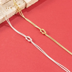 Detailed close-up of gold and silver knot snake chain bracelets on red background