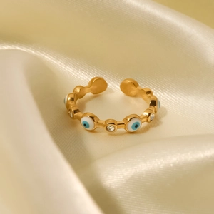 Macro shot of 18K gold plated evil eye ring with blue enamel and zircon on silk