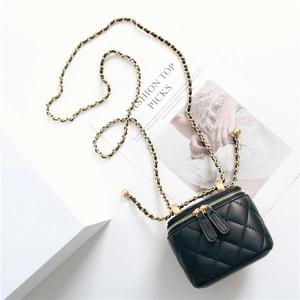 Detail of black quilted leather mini vanity bag with gold ball chain and dual zippers