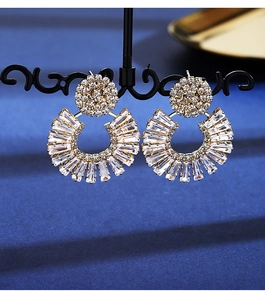 Macro detail of fan-shaped gold earrings featuring sparkling zircon crystal inlays