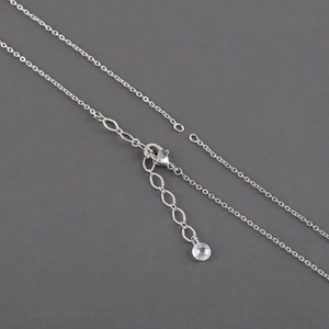 Macro detail of silver-plated cross chain with lobster clasp and beaded extension