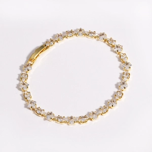 Macro view of gold-plated tennis bracelet with square-cut cubic zirconia and snap clasp