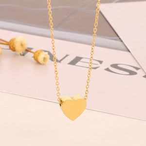 Close-up of a 3D gold heart pendant on a delicate chain necklace with romantic decor