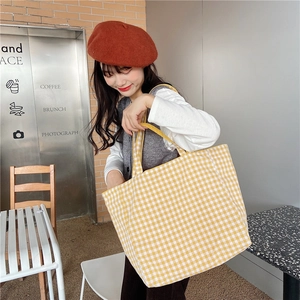 Casual yellow and white checkered canvas tote bag shown in a lifestyle cafe setting