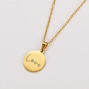 Gros plan d'un pendentif rond en or 18 carats avec gravure Love et fine chaîne dorée