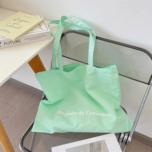 Detalle del bolso tote de lona verde menta con texto Magasin de Croissants en una silla
