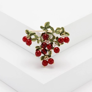 Charming red cranberry berry brooch with gold metal leaves on a white background