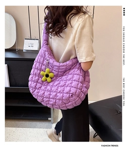 Detail of purple quilted cloud tote bag with bright yellow sunflower charm accessory