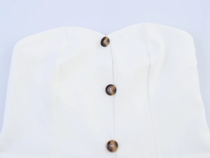 Detail of white tube top with brown tortoiseshell buttons and smooth fabric texture