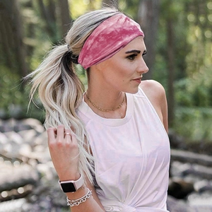 Pink tie-dye sports headband worn by a woman in a natural outdoor forest setting
