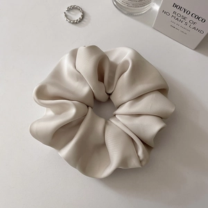 Detail of elegant champagne satin scrunchie with silky texture and soft glossy finish